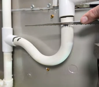 Cutting the old PVC condensate trap out with a hand saw