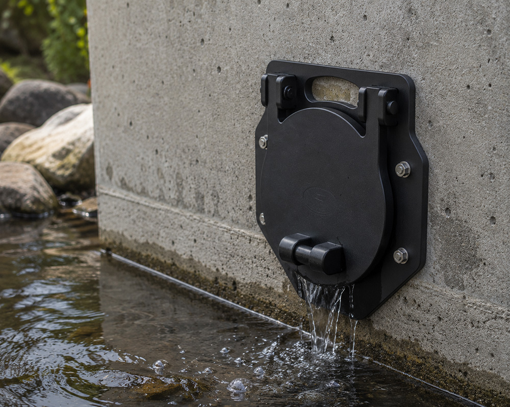 Fernco wall mount flap valve on a concrete headwall discharging into a stream